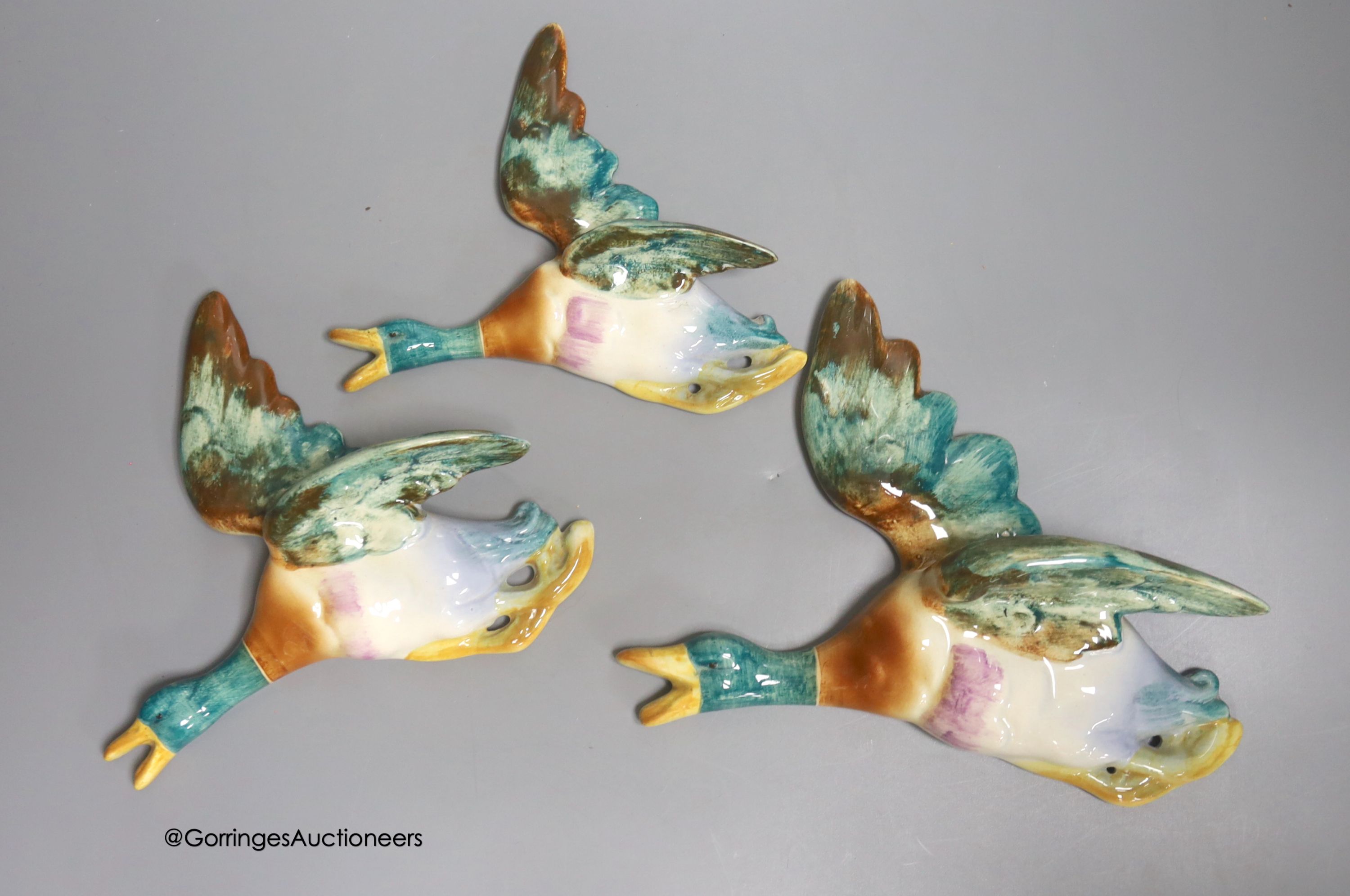A graduated set of three earthenware wall-hanging flying ducks, widest 20cm